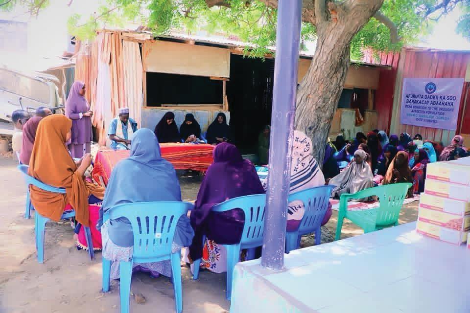 Community members meeting outdoors in the shade of a tree